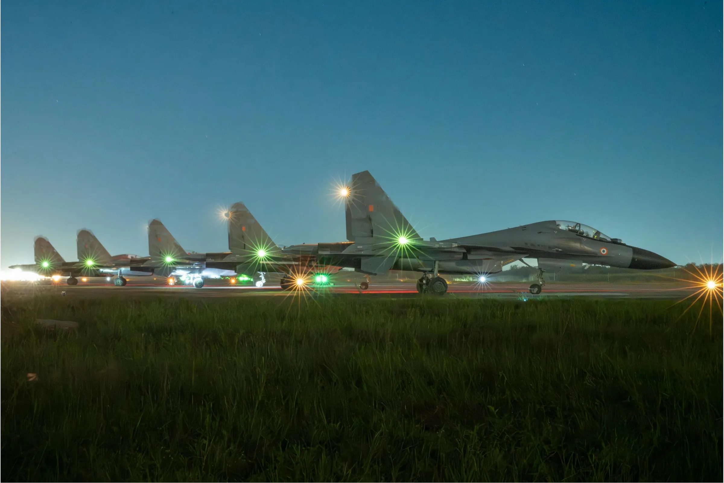Su-30MKI fighters lined up on the runway at dusk
