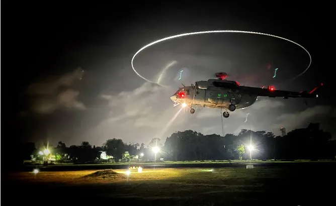 An Air Force helicopter hovering low over a landing ground at night